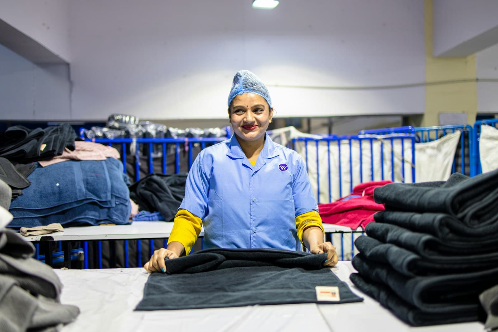 Trabalhadora dobrando peças de roupa em uma fábrica de confecção