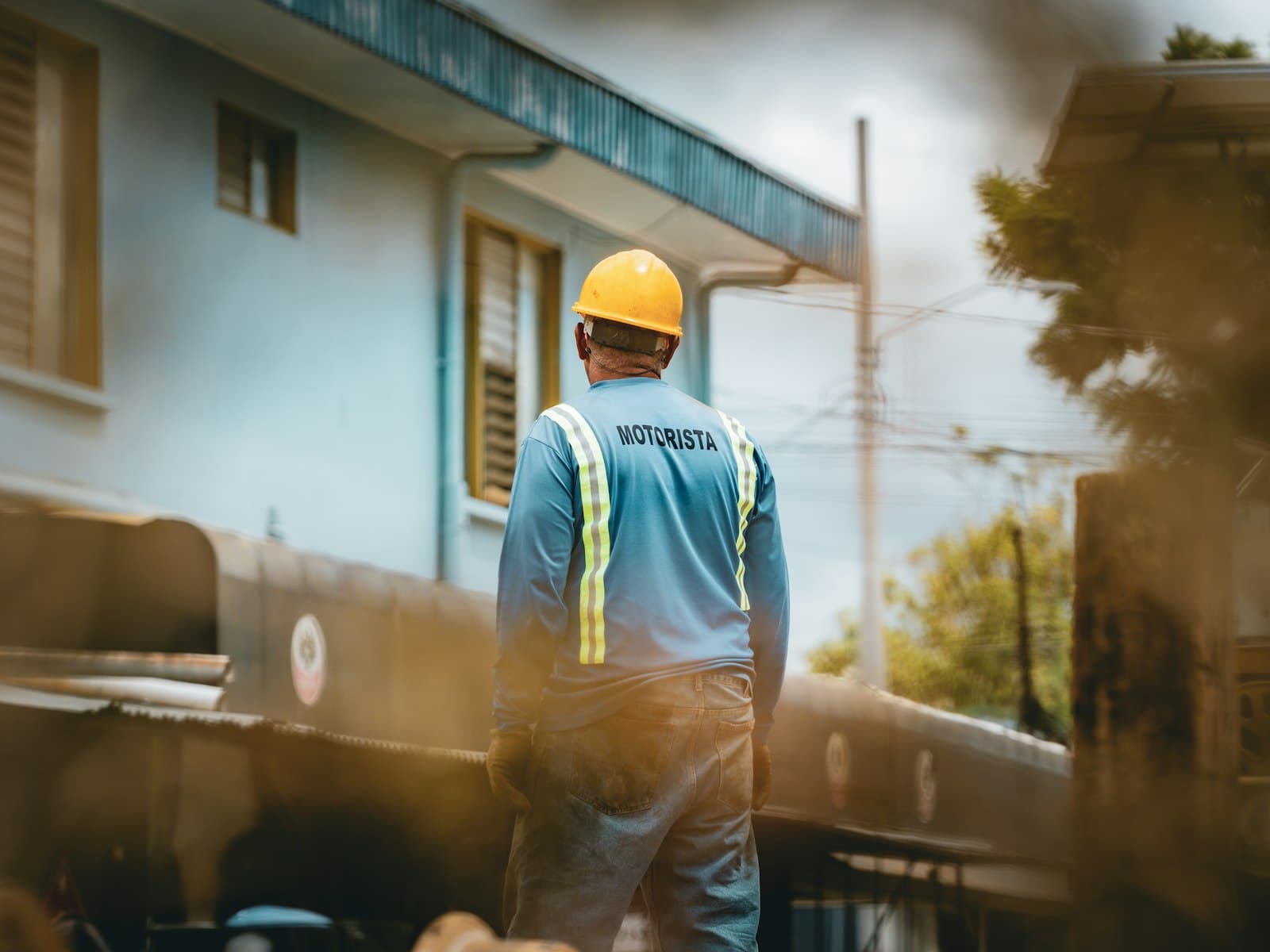 Trabalhador de capacete e colete de segurança em um canteiro de obras, olhando para o lado